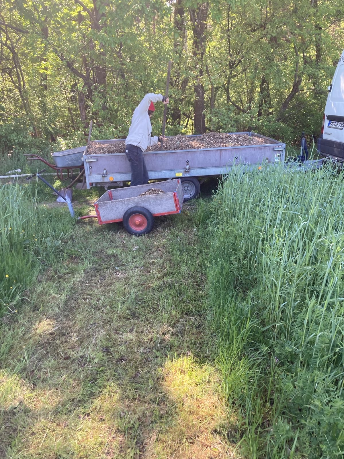 Mensch am Rand eines Ackers, mit Schaufel im Anhänger